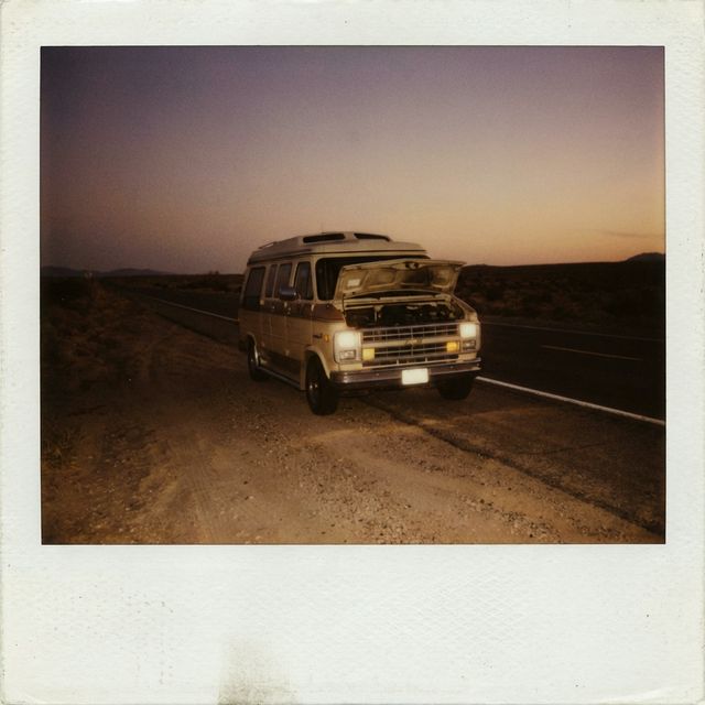 A conversion van broken down on a dusty desert shoulder